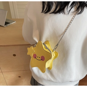 Detail of yellow star-shaped crossbody bag with smiling face design and silver chain