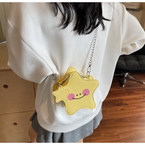 Detailed close-up of yellow star-shaped crossbody bag with smiling face and chain strap