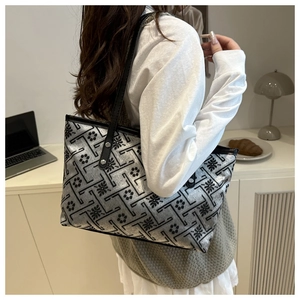 Silver tote bag with geometric floral patterns shown worn on shoulder in a modern room