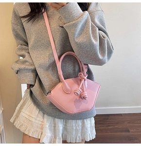 Detailed view of a pink fan-shaped bag with a unique knot handle and thin crossbody strap