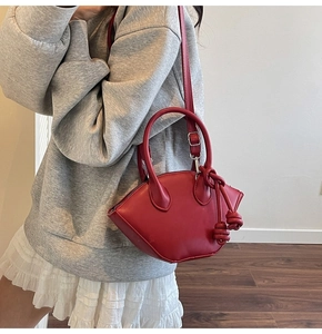 Detail of red leather city shell bag with unique knots shown as a crossbody bucket style