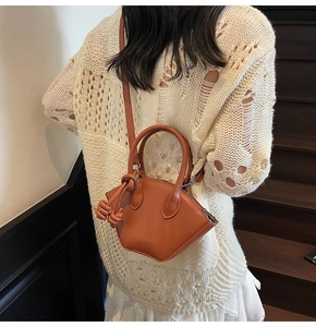 Close-up of caramel leather mini tote bag with knotted strap detail and trapezoid shape