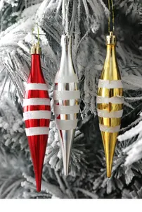 Close-up of red and gold striped conical Christmas tree ornaments hanging on snowy branches
