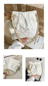 Detailed view of white quilted bucket bag with gold chain and tulip charm accessory