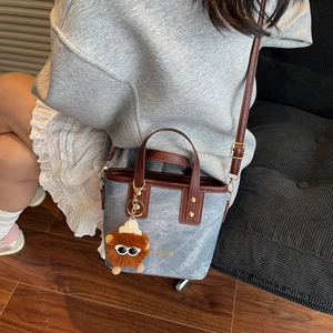 Denim and leather bucket bag with lion charm shown as crossbody and handbag style
