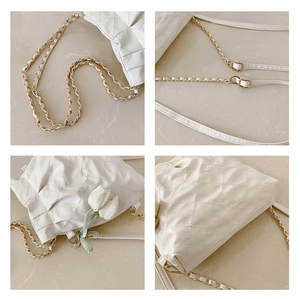 Close-up of quilted white leather texture with gold chain strap and tulip charm detail