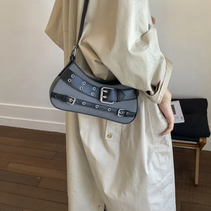 Chic Y2K denim and leather shoulder bag with punk buckles and metal eyelets on a model