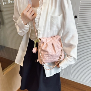 Pink quilted crossbody bag with gold chain strap and floral tulip charm shown on model