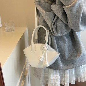 Minimalist white semi-circular tote bag with decorative rope knot and metallic zipper
