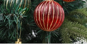 Makro-Detail roter und grüner gestreifter Weihnachtskugeln mit Goldglitzer auf Zweigen