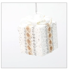 Close-up of a white glitter gift box ornament with burlap ribbon and sparkling silver rhinestones
