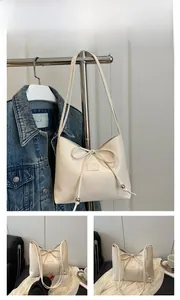 Dettaglio borsa a secchiello bianca con fiocco e accenti di perle argentate estiva
