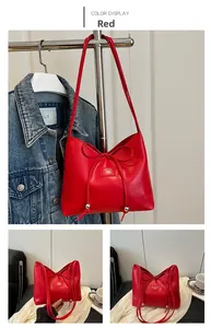 Dettagli della borsa a secchiello rossa con fiocco decorativo, sfere di metallo e logo