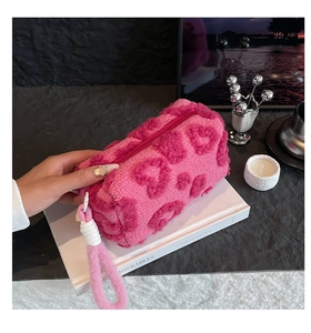Detalle del neceser rosa de peluche con corazones, cremallera y asa de transporte pro