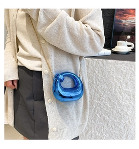 Detail of electric blue crescent mini bag with mirror finish and gold chain strap