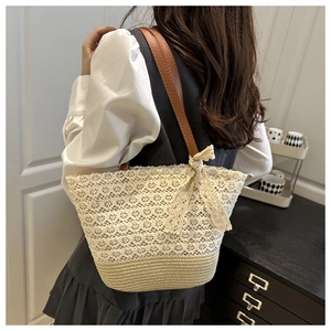 Detail of crochet lace tote bag with straw base and stylish brown leather strap