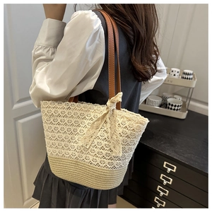 Detail of beige lace woven tote bag with brown leather handles and a bow accent