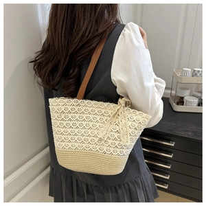 Detailed close-up of woven straw tote bag with white crochet lace and bow accent