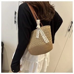 Vue détaillée du sac cabas en paille tissée avec nœud en dentelle et bandoulière en cuir