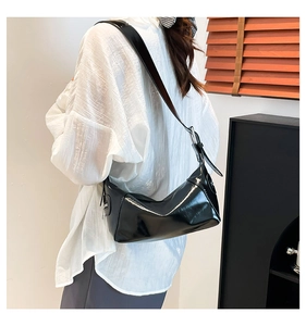 Bolso hobo de charol negro brillante llevado por una modelo en un interior elegante