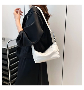 Detail view of a white PU leather baguette bag on a shoulder with adjustable strap and silver buckle