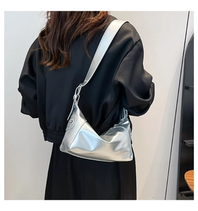 Close-up of metallic silver underarm bag with glossy finish and wide shoulder strap