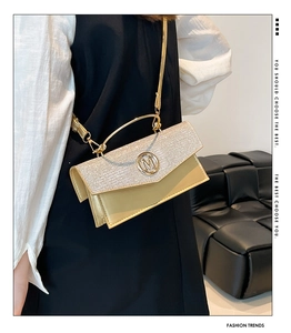 Detail of glittery patchwork crossbody bag with metallic M logo and round handle