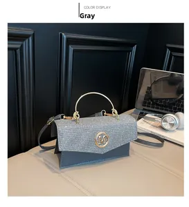Detail of grey sparkling tote bag featuring gold M logo and curved metal handle