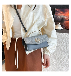 Detail of crossbody bag with silver glitter flap and gold M logo shown on a model