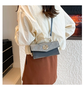 Detailed view of women's envelope bag with glitter flap and metal M logo on shoulder