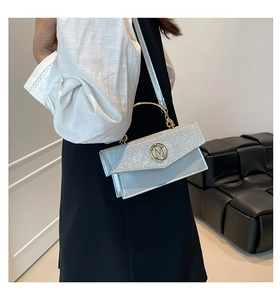 Close-up of sequin patchwork flap and golden M-logo on light blue leather crossbody bag