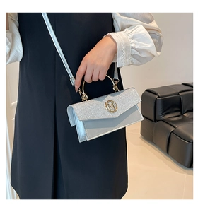 Close-up of silver crossbody bag with glitter flap and circular metal M logo handle