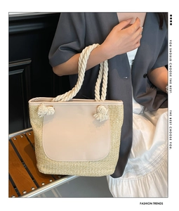 Detail of woven straw tote bag with beige leather patch and decorative tassel rope handle