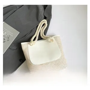 Detail of woven straw tote bag featuring white leather pocket and thick rope handles