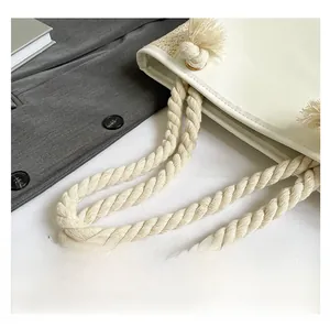Detail of twisted rope handle and gold hardware on cream woven bucket handbag