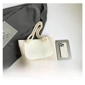 Detail of straw woven tote bag featuring white leather pocket and thick rope handle