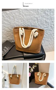Detail of a brown woven tote bag featuring smooth leather panels and white cotton rope handles