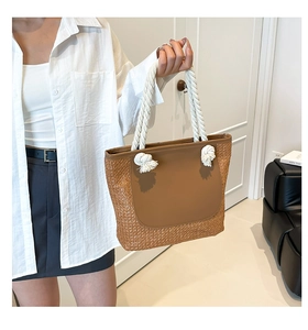 Detail of summer straw tote bag with brown patchwork texture and white rope handle
