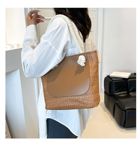 Detail of woven straw and brown leather tote bag with white cotton rope handle