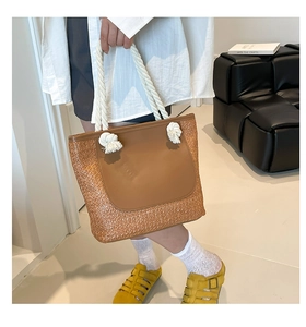 Detail of large straw tote bag with brown PU patch pocket and white rope handles