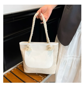 Detail of woven straw tote bag with smooth white panel and thick rope handles for summer