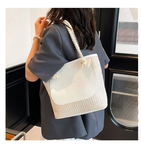 Detail of white woven bucket bag with thick cotton rope handles and leather patch