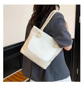 Detailed view of straw tote bag with white leather patch and cotton rope straps