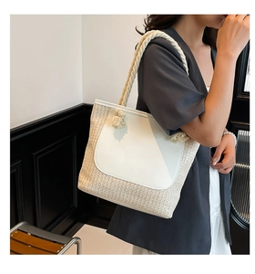 Detail of woven straw tote bag with white leather trim and twisted rope shoulder strap