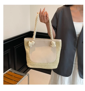 Detail of woven straw tote bag with cream leather panel and rope knotted handles