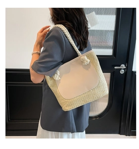 Detail of woven beach tote with white rope strap and leather patch on model