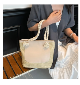 Detail of straw tote bag with beige leather patch and rope handle on fashion model