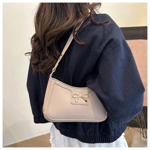 Vista posteriore della borsa a spalla beige con fiocco in pelle opaca indossata dalla modella