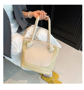 Detail of hand-woven straw tote with beige leather pocket and soft cotton rope handles