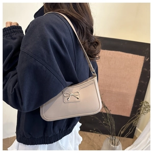Detailed view of apricot underarm bag with stylish silver bow buckle and textured finish